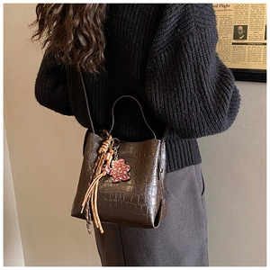 Close-up of retro crocodile pattern bucket bag with bear pendant and woven tassel