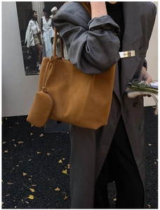 Detail of tan leather tote bag with vertical stitching and small matching zipper pouch