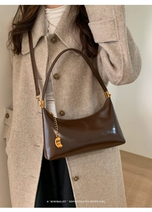 Detail view of vintage dark brown faux leather hobo bag with a gold fashion chain pendant