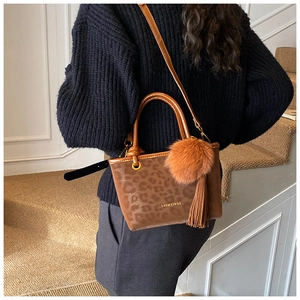 Détail du sac seau à imprimé léopard avec pompon en fourrure et pampille à franges