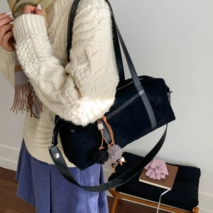 Detalle de bolso Boston de ante negro con remaches y pompón de peluche estilo otoñal