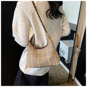 Detail of vintage houndstooth hobo bag with woven chain strap and leather piping