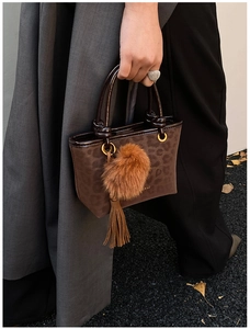 Détail d'un sac à main léopard avec pompon en fausse fourrure marron et pendentif