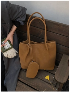 Detail of matte brown tote bag set on a vintage bench with autumn leaves accent