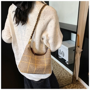 Detailed back view of a houndstooth crescent bag with woven metal chain strap worn by model