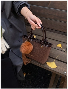 Détail d'un sac seau léopard avec pompon en fourrure et franges en cuir brun