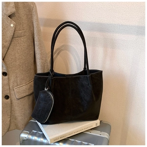 Detail of black tote bag set with contrast stitching on metallic luggage