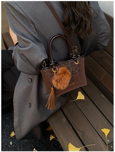 Détail du sac à bandoulière léopard avec glands marrons et charms en boule de fourrure