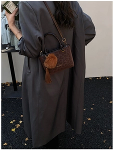 Détail du sac à main léopard avec pompon en fourrure et franges sur un manteau gris chic
