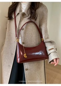 Detail of dark red vintage shoulder bag featuring gold fashion zipper and glossy leather texture