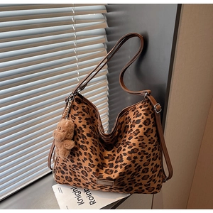 Detail of leopard print hobo bag with brown leather strap and plush bear pendant