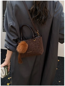 Détail du sac seau léopard avec breloque peluche et pompon sur une veste de blazer grise