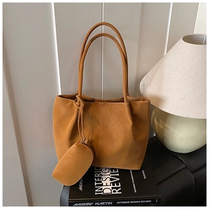 Detail of caramel tote bag with hanging coin purse on interior design book