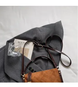 Detail of brown suede crossbody bag with rhombus stitching and adjustable strap