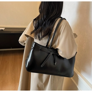 Detailed view of the black minimalist tote bag with chic bow knot on a model's shoulder