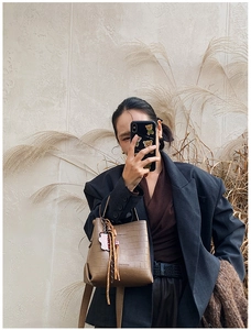 Macro shot of the brown crocodile pattern texture and tassel detail on the stylish bucket bag