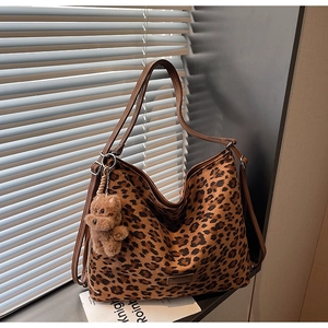 Macro shot of leopard print tote bag with metal logo and plush bear pendant detail