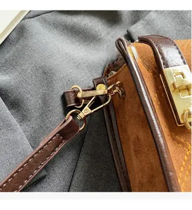Close-up of premium gold hardware and brown suede texture on this square shoulder bag