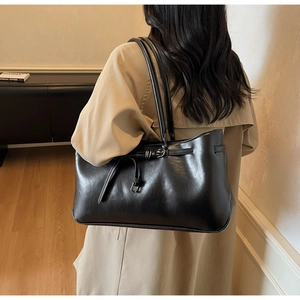 Detail of glossy black leather tote bag with elegant buckle and drawstring accents