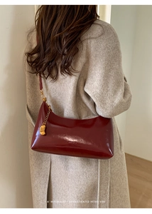 Macro view of vintage burgundy baguette bag with gold chain and smooth leather texture