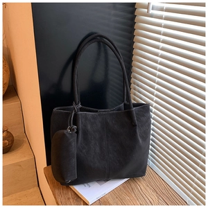 Detail of black suede tote bag featuring contrast white stitching and matching mini pouch