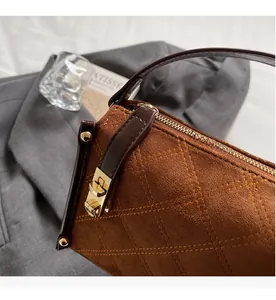 Detail of brown quilted suede handbag showing smooth golden zipper and refined texture