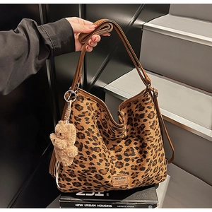 Close-up of leopard print shoulder tote bag featuring a cute plush bear pendant accessory