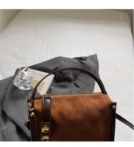 Macro detail of brown suede quilted handbag with golden twist lock and leather handle