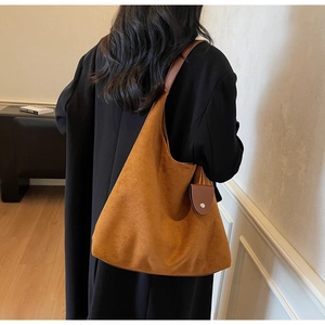 Detail of caramel suede hobo bag showing slouchy silhouette and matching pouch on black coat