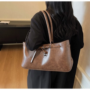Detail of dark brown vintage faux leather tote bag with stylish metal buckle straps