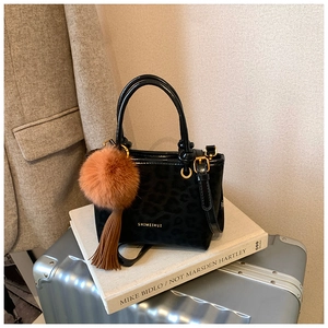 Détail du sac seau noir motif léopard avec finitions dorées et charm pelucheux