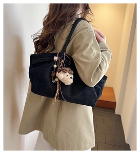 Detail of black suede tote bag with cute dog plush charm and colorful bead strap