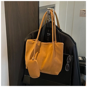 Detail of a brown faux leather tote bag with a small matching pouch on a black blazer
