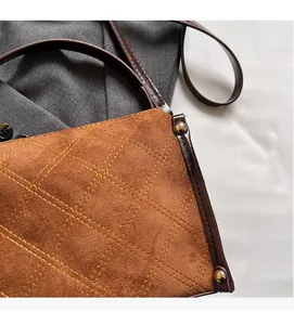 Detail of brown quilted faux suede handbag with gold rivets and leather trim stitching
