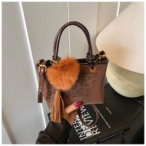 Détail d'un sac à main léopard marron avec pompon en peluche et pendentif à franges