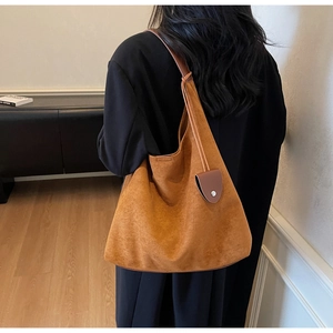 Close-up of brown suede tote bag featuring slim straps and a circular charm detail