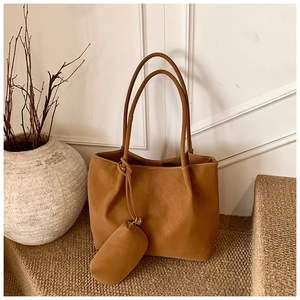 Detail of caramel tote bag with matching pouch on textured jute steps for minimalist style