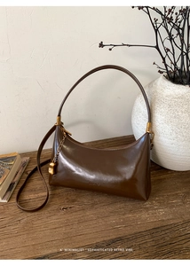 Detail of dark brown retro underarm bag on a wooden table with vintage decor