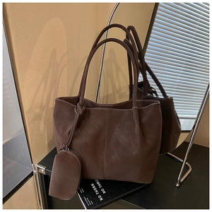 Detail of dark brown tote bag featuring white contrast stitching and matching pouch charm