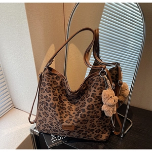 Detail of leopard print tote bag with brown straps and cute plush bear charm accessory