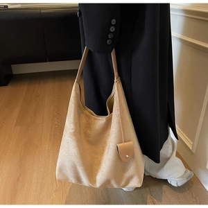 Detail of light brown suede tote bag with heart pendant accessory and soft texture