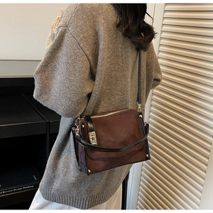 Quilted brown suede crossbody bag with gold lock shown on model's side for size