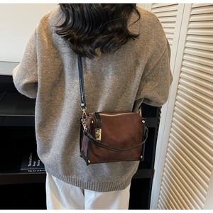Detail of dark brown quilted square bag with gold hardware worn as a crossbody on model