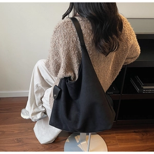 Detail of a black large tote bag with a small detachable pouch shown in a daily scene
