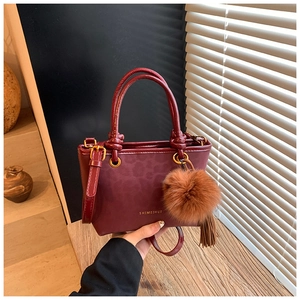 Détail du sac seau bordeaux avec gaufrage léopard et pompon en peluche décoratif