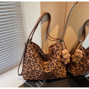 Detail of leopard print tote bag with brown straps and cute plush bear keychain