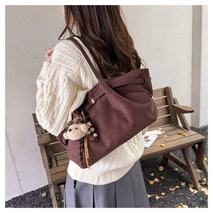 Close-up of a vintage brown suede tote bag with a cute bear charm and tassel details