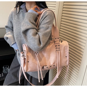 Dettaglio della borsa rosa chiaro con frange e borchie indossata da una modella