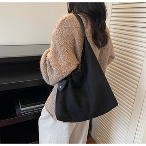 Close-up of a large black tote bag with wide straps and buckle detail for women