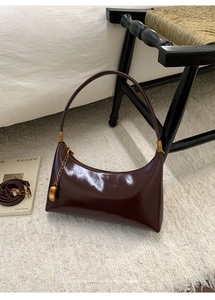 Close-up of vintage dark brown glossy patent leather half-moon bag with gold hardware detail